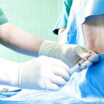 Healthcare professional administering an injection to a patient in a surgical setting