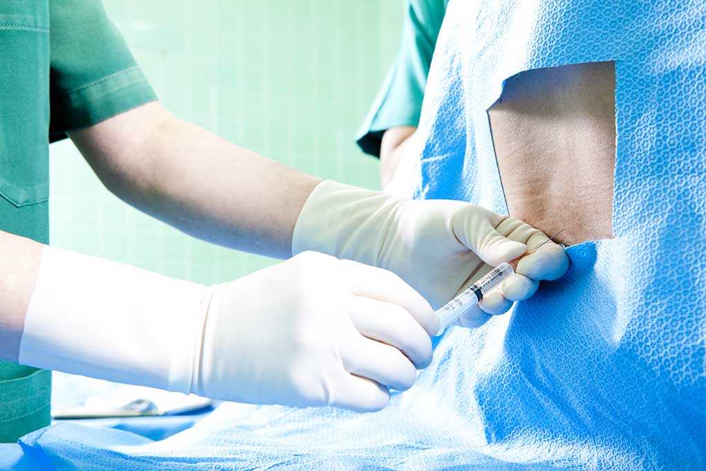 Healthcare professional administering an injection to a patient in a surgical setting