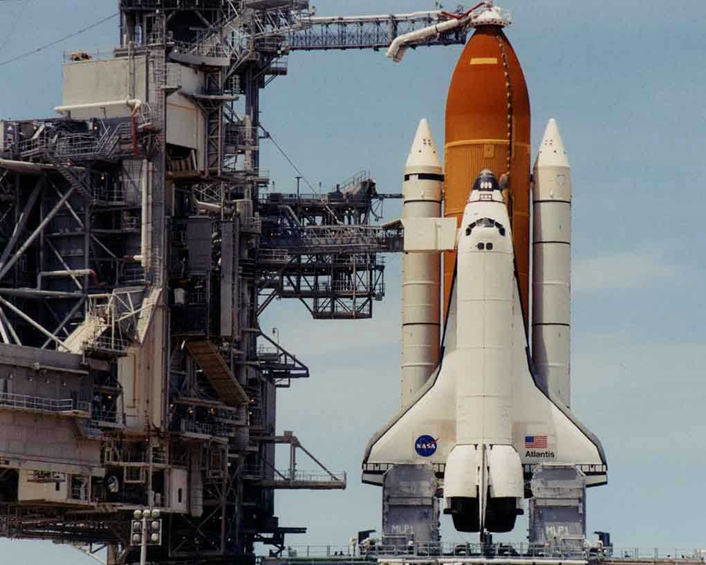 Space shuttle on launch pad with support structure.