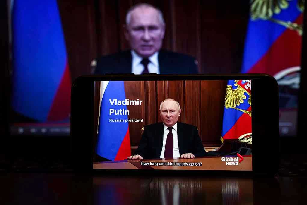 Man speaking on screen with Russian flag background.