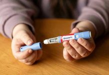 Hands holding an Ozempic injection pen.