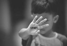 Child holding up hand with STOP! written on palm.