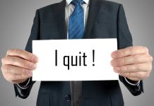 A man in a suit holding a sign that says I quit!