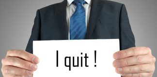 A man in a suit holding a sign that says I quit!