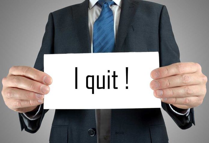 A man in a suit holding a sign that says I quit!