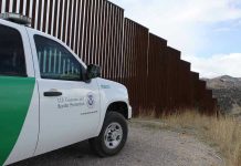 Campus Meltdown After Border Czar Erupts Border protection vehicle near a large metal fence.