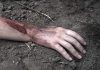 Injured arm partially buried in dirt.