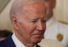 J6 Pipe Bomb Arrest: Biden Incompetence Exposed Man in a suit looking thoughtful.