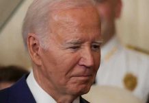 J6 Pipe Bomb Arrest: Biden Incompetence Exposed Man in a suit looking thoughtful.