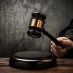 A judges gavel poised to strike a sound block