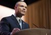 Bongino’s FBI Role Sparks Massive Outcry A man in a suit speaking at a podium during a conference