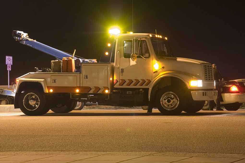 Tow truck with flashing lights parked at night