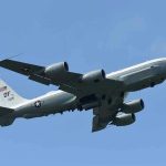 Military aircraft flying in clear blue sky.