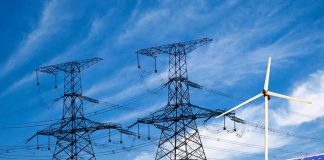 Power lines, solar panels, and wind turbine against sky.