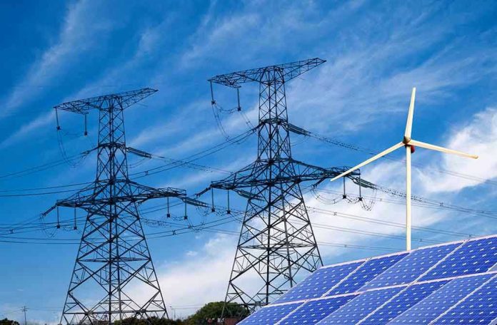 Power lines, solar panels, and wind turbine against sky.