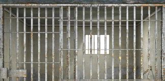 Empty rusty prison cell with a small window.