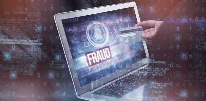 665585107 Person holding credit card near laptop displaying Fraud.