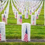 Rows of grave markers adorned with American flags in a military cemetery