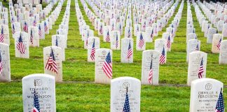 Rows of grave markers adorned with American flags in a military cemetery
