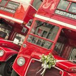 Two red double-decker buses decorated for a wedding with Just Married signs