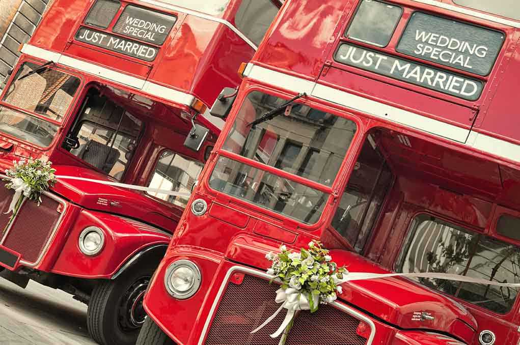 Two red double-decker buses decorated for a wedding with Just Married signs