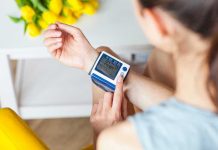 Person checking wrist blood pressure monitor indoors