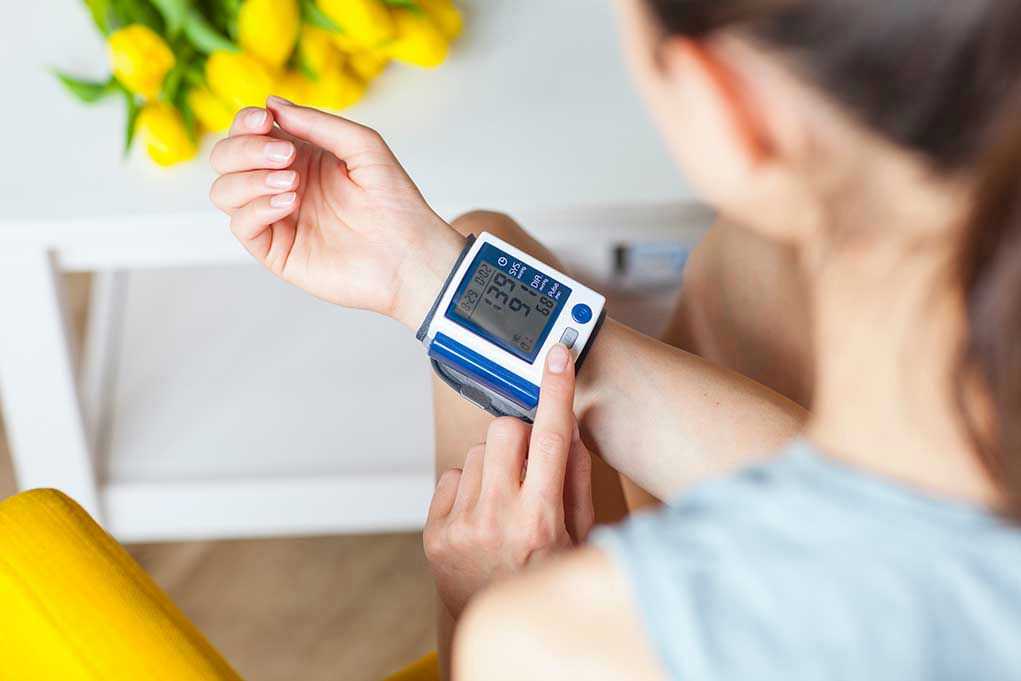 Person checking wrist blood pressure monitor indoors