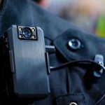 Cop Turned Insider—Gang Intel Shock Body camera attached to a black uniform.