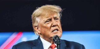 Man in suit speaking at a microphone.