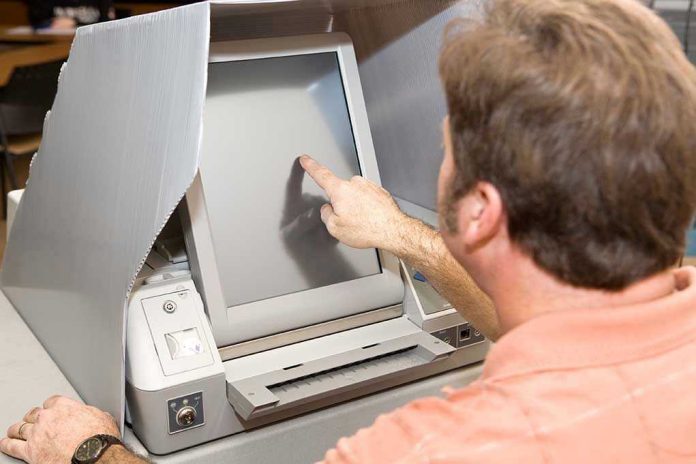 Person using touchscreen voting machine in polling booth.