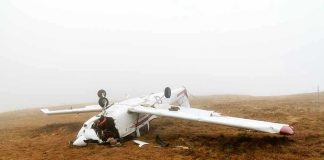 Overturned crashed airplane on grassy field.