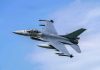 Jet fighter flying through clear blue sky.
