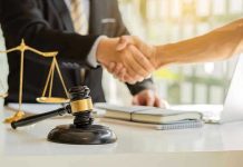 Hands shaking over legal documents with gavel and scales.