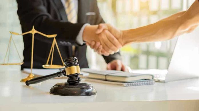 1936290997 Hands shaking over legal documents with gavel and scales.