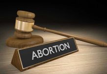 Gavel and sign reading Abortion on a wooden surface.