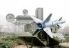 Military missile launcher with radar systems in a foggy field.