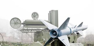 Military missile launcher with radar systems in a foggy field.