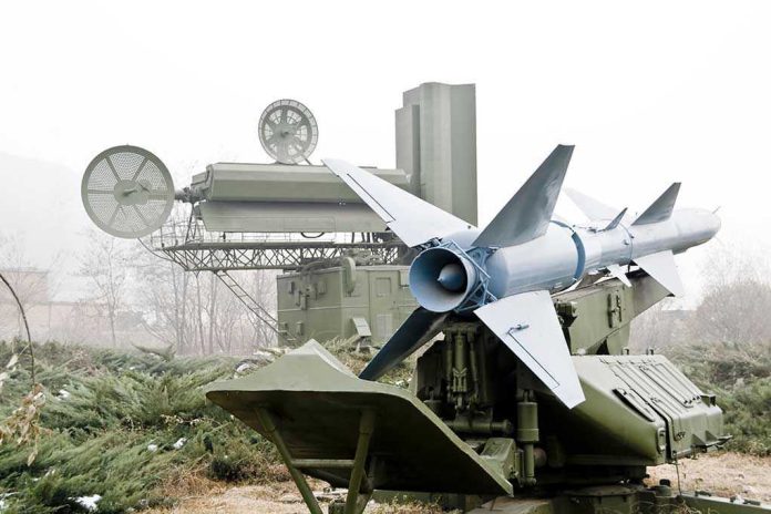 Military missile launcher with radar systems in a foggy field.