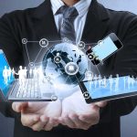 Businessman holding a laptop and tablet with digital icons representing global connectivity