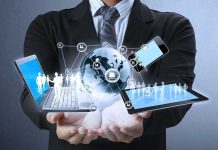 Businessman holding a laptop and tablet with digital icons representing global connectivity