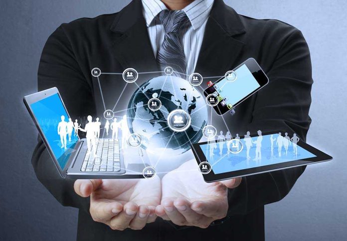 Businessman holding a laptop and tablet with digital icons representing global connectivity