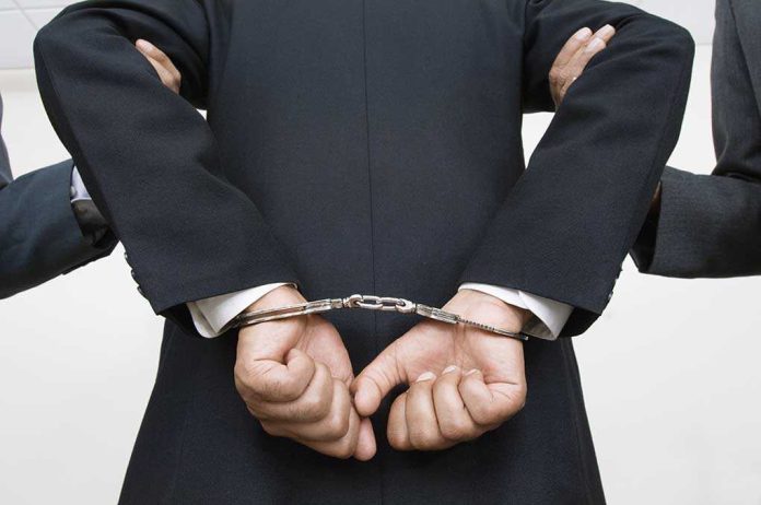 shutterstock_121141399 A person in a suit with hands cuffed behind their back