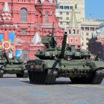 Military tanks on parade in Red Square with historical buildings in the background