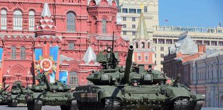 Military tanks on parade in Red Square with historical buildings in the background