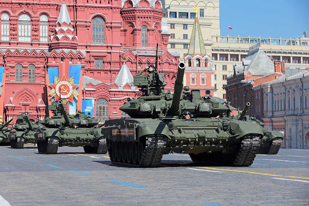 Military tanks on parade in Red Square with historical buildings in the background