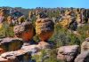 Unique rock formations surrounded by greenery under a clear blue sky