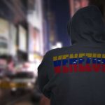 Person in hoodie with Venezuela text standing in a blurred city street