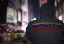 Person in hoodie with Venezuela text standing in a blurred city street
