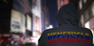 Person in hoodie with Venezuela text standing in a blurred city street