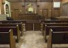 Interior view of an empty courtroom with wooden benches and a judges bench